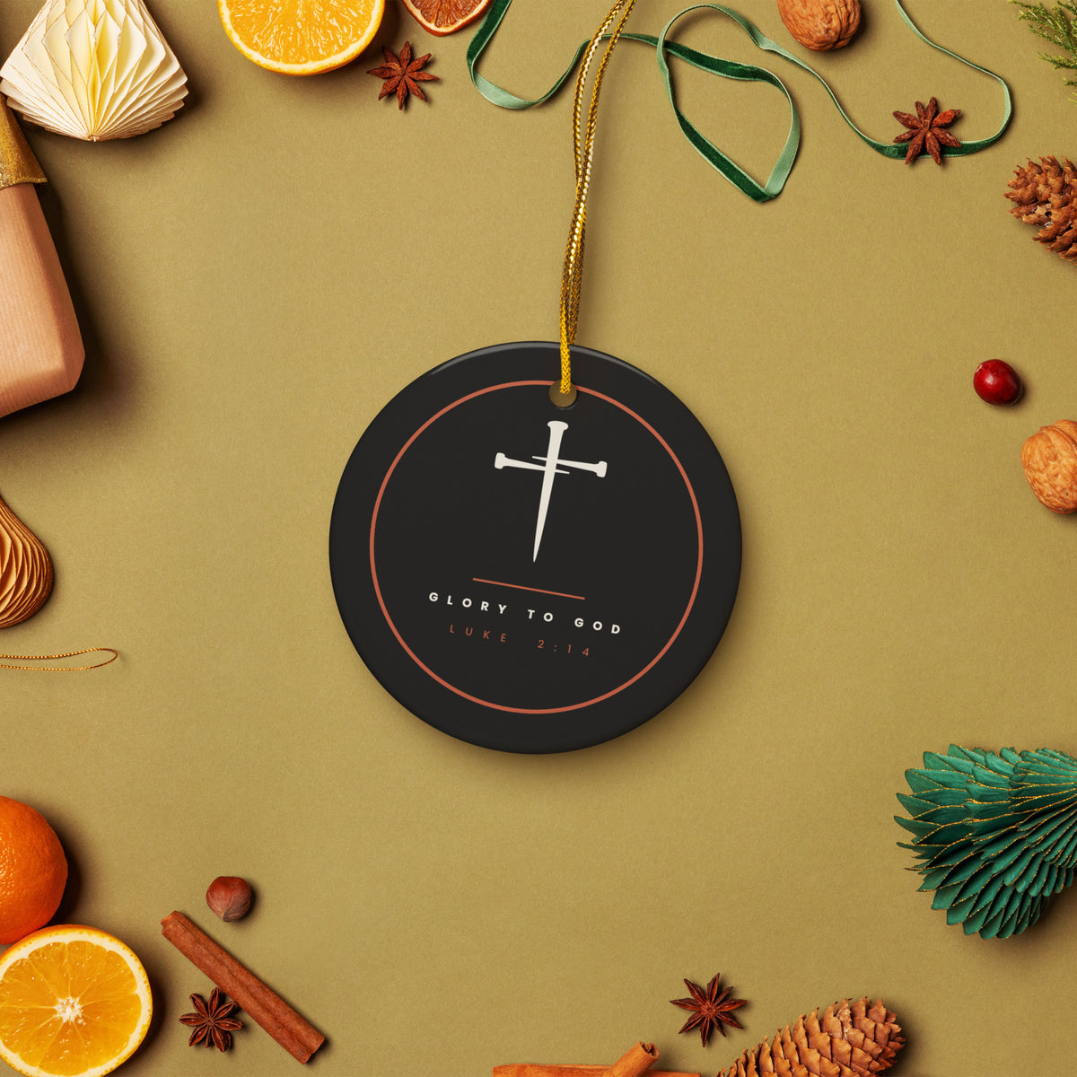 Glory To God Luke 2:14 ceramic ornament hanging among pine, oranges and cinnamon in a holiday flat lay