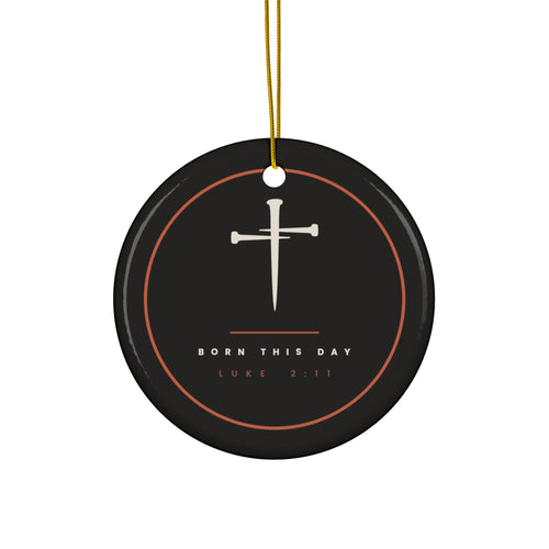 Black ceramic Christmas ornament with cream nail cross and Born This Day, Luke 2:11, inside a copper ring, hanging from a gold string