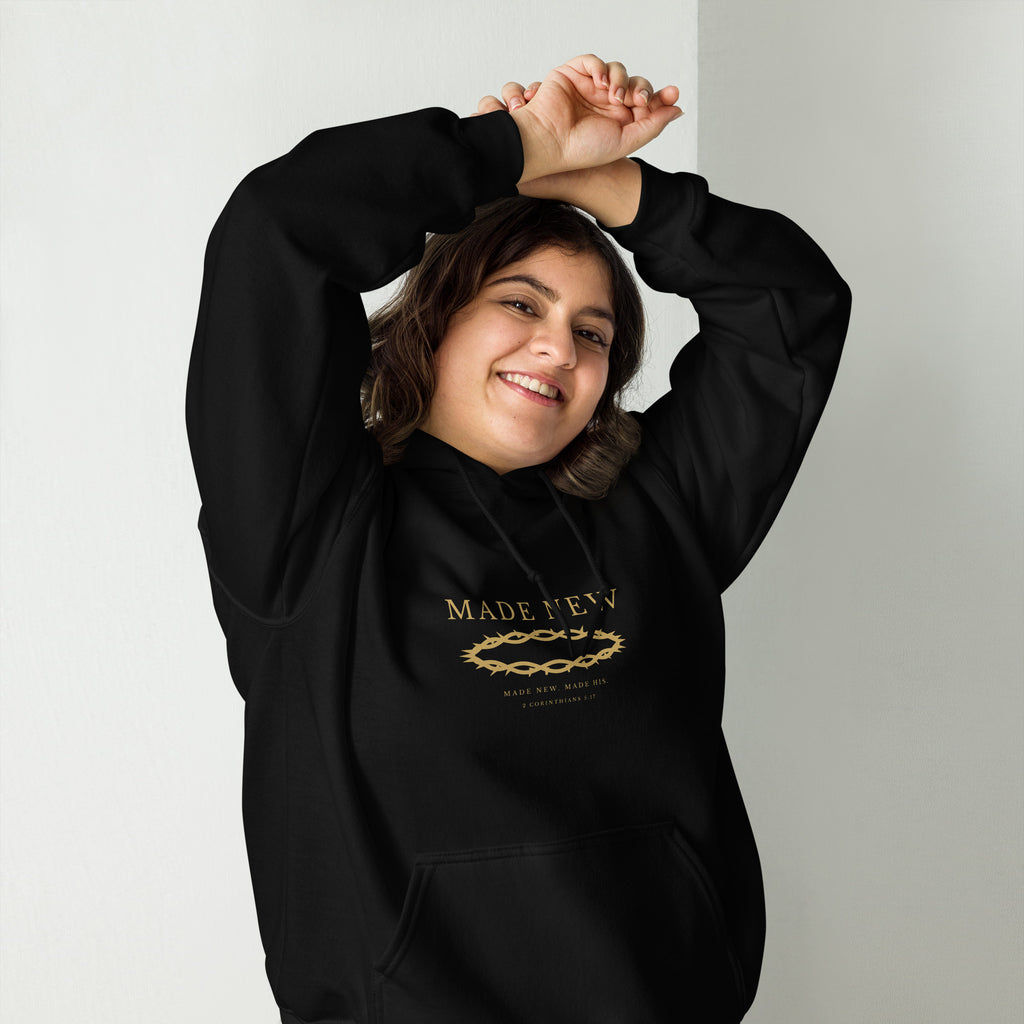 Woman wearing the Made New black hoodie, arms raised, gold chest print visible