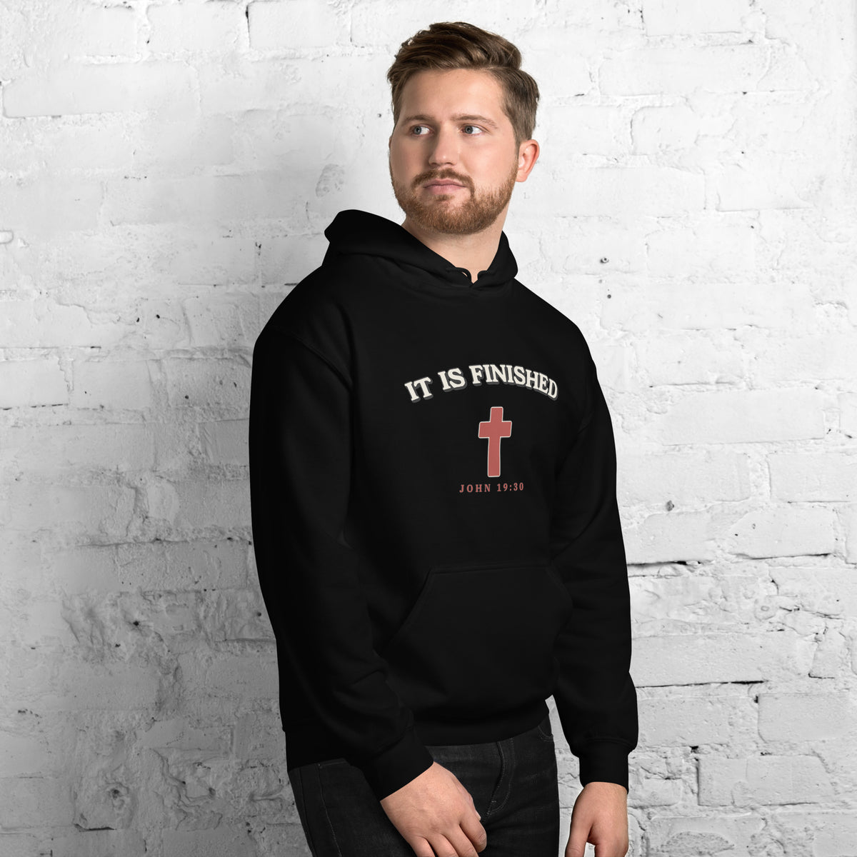 Man wearing the It Is Finished black hoodie with cream arched lettering and red cross, front view