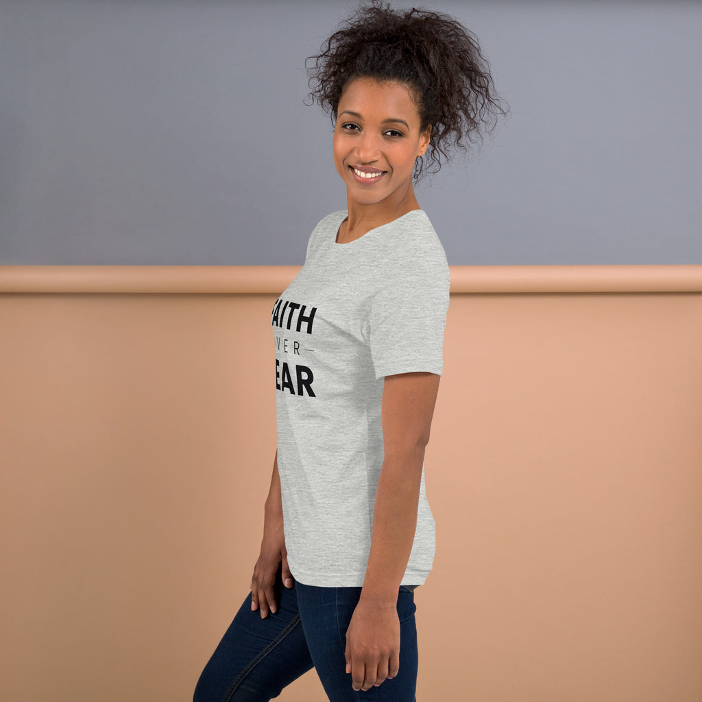 Faith Over Fear T-Shirt — model in the athletic heather tee against a warm backdrop, side view