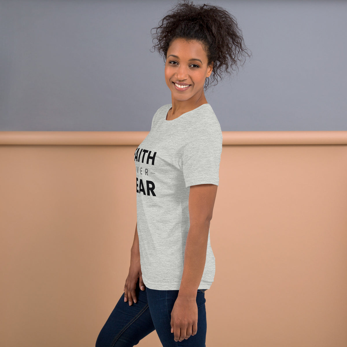 Faith Over Fear T-Shirt — model in the athletic heather tee against a warm backdrop, side view