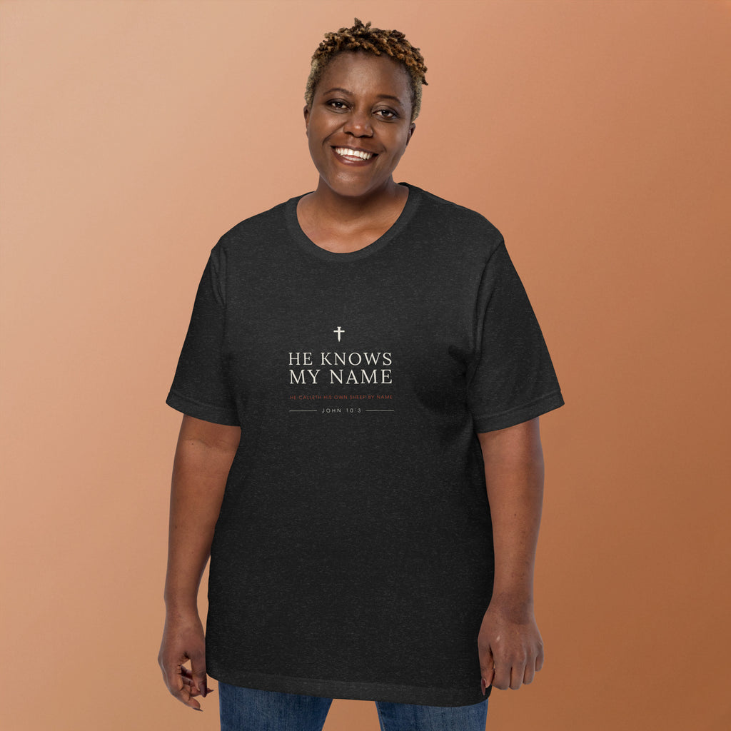 He Knows My Name T-Shirt — model wearing the black heather tee, front view showing the cross and lettering
